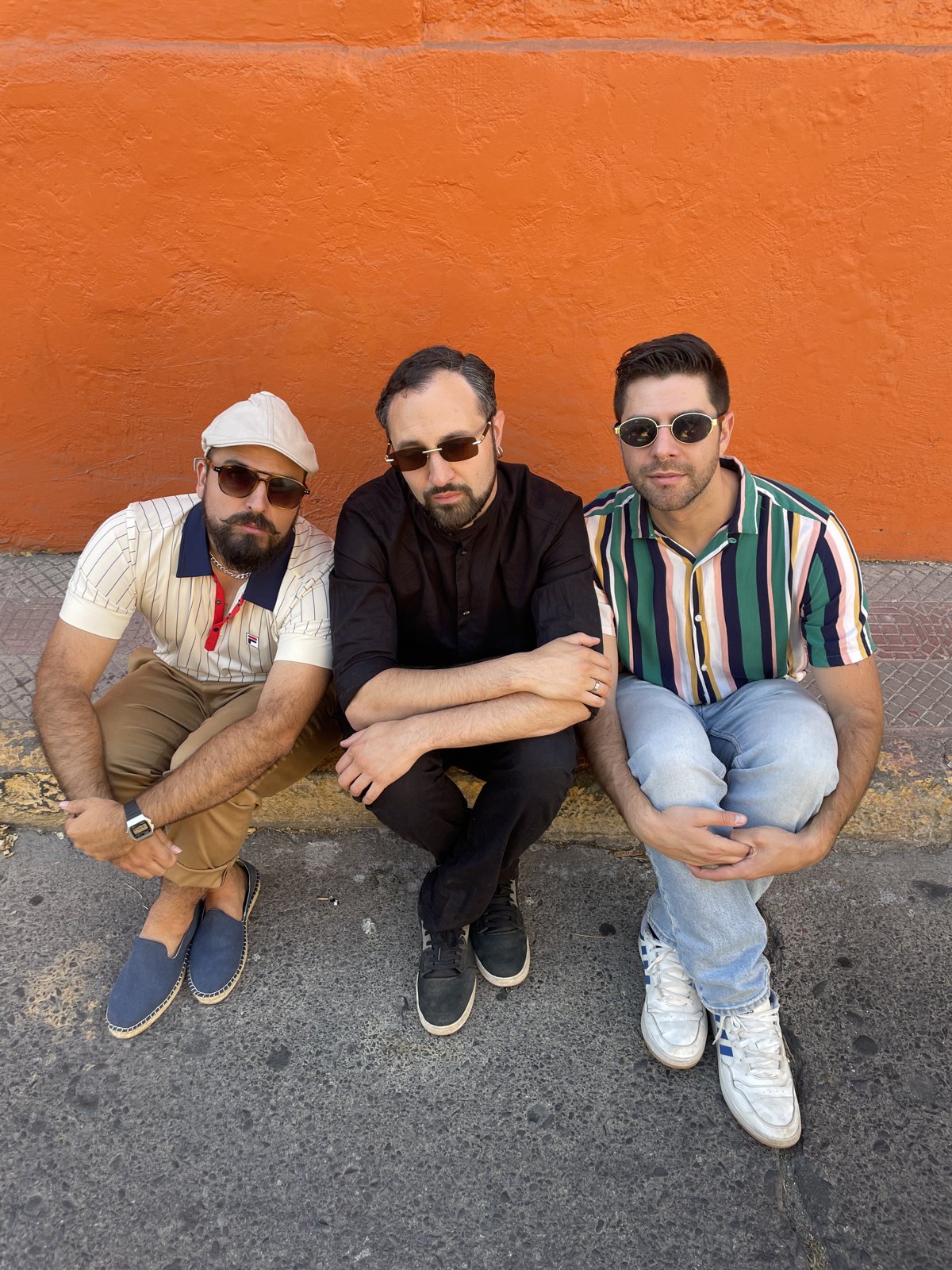 Los tres integrantes de Los Semejantes frente a un muro naranja